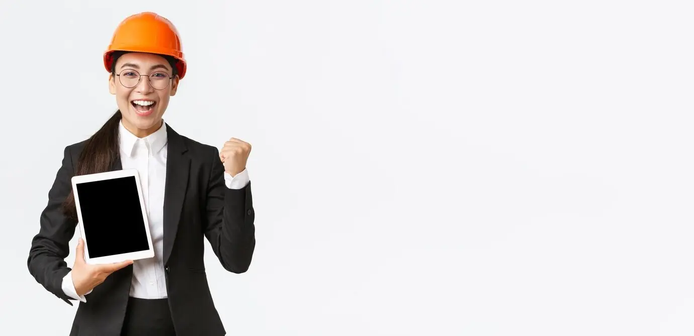 Erfolgreiche, siegreiche Ingenieurin und Bauleiterin in einer Fabrik, mit Schutzhelm und Business-Anzug.